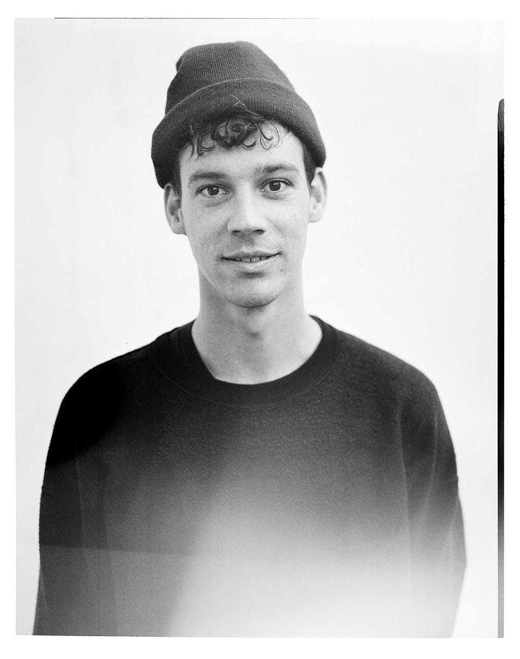 Black and white portrait of Ben Raemers wearing a beanie & black t-shirt.