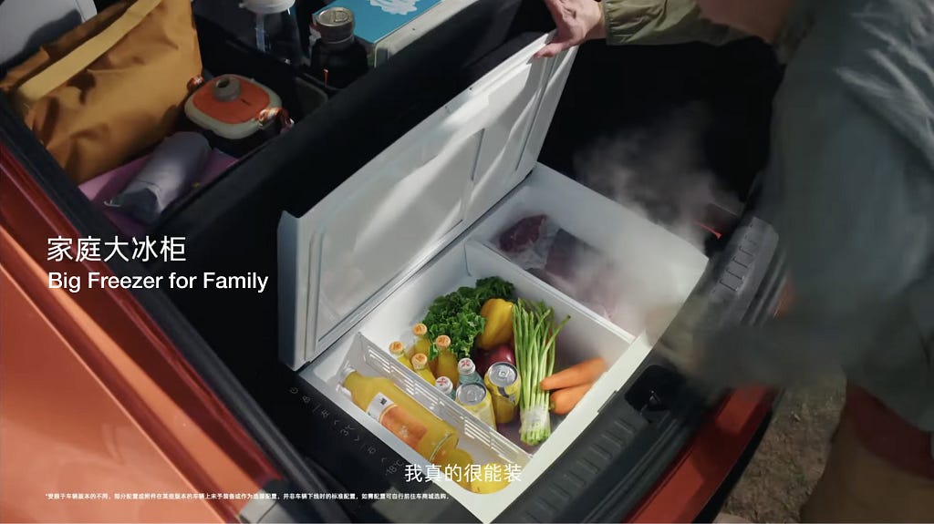 A large built-in freezer in the trunk of a car, labeled “Big Freezer for Family,” stocked with fresh produce, beverages, and meat, designed for family convenience and outdoor activities.