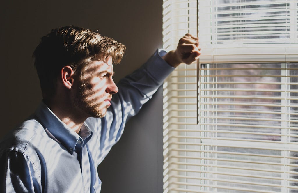 Man looking out the window who appears miserable