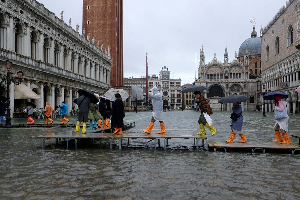 People walk on a catwalk in the flooded St. Mark’s Square, Venice