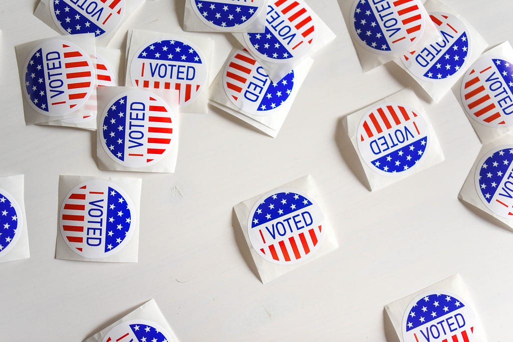 “I voted” stickers donning US stars and stripes, scattered across a white tabletop