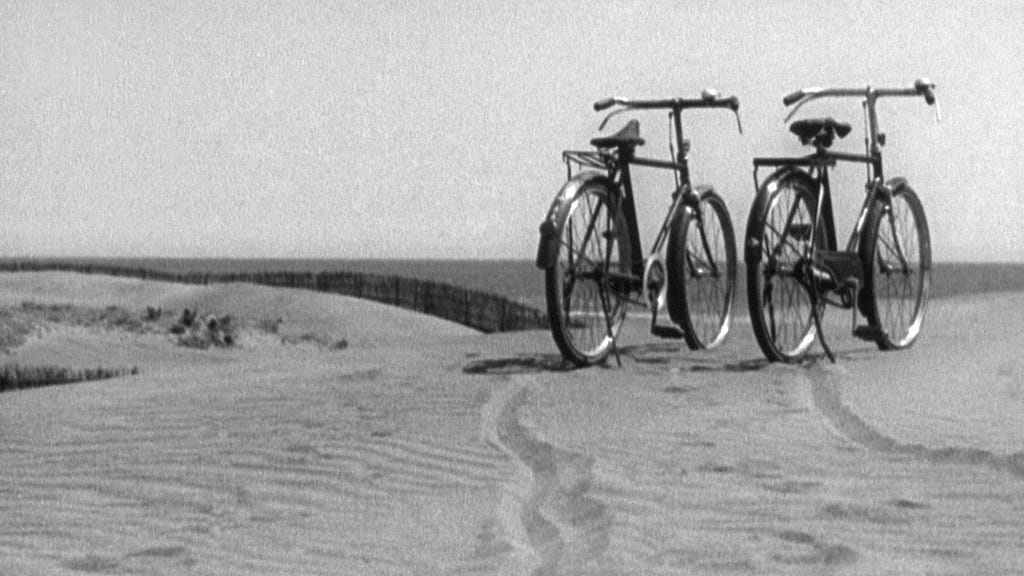 Two bicycles standing together on a sand dune.