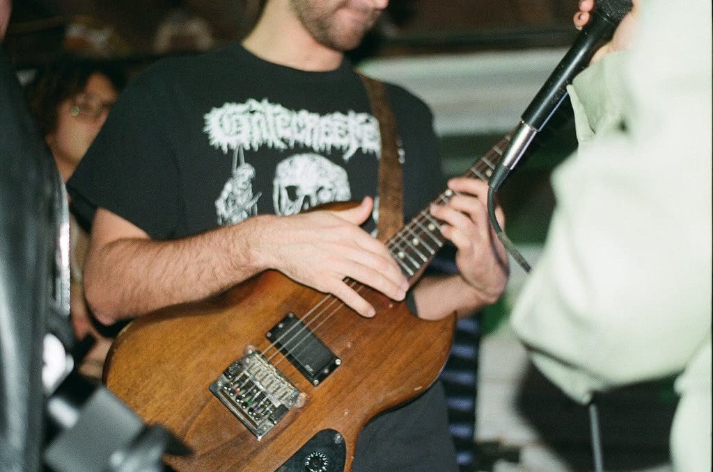 Close-up shot of a musician playing guitar at a Rutgers basement show