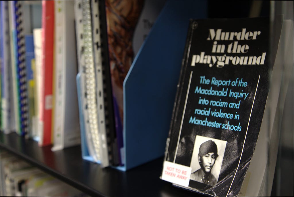 A shelf of books and documents in the AIU Race Centre. A book titled ‘Murder in the playground’ faces toward the camera.