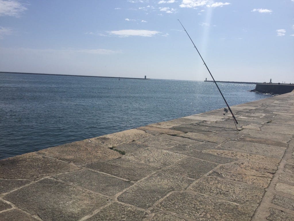 Blue skies and sparkly ocean with foreground of a stone pier or fondamenta