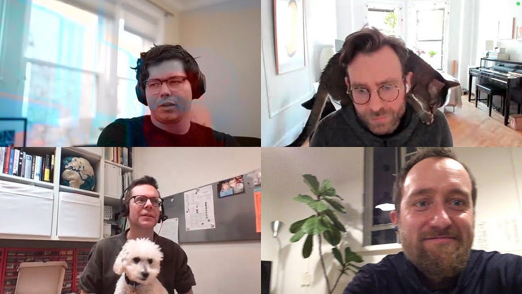 The four team members Justin Vickers, Alex Hague, Matt Leacock and Matteo Menapace in front of their computers during a weekly video call. Alex is joined by his cat, while Matt is joined by his dog.