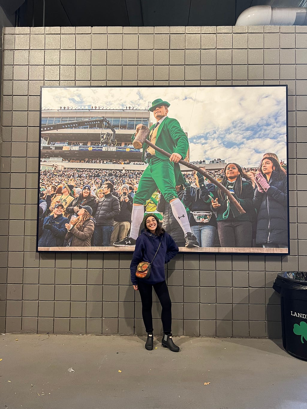 Marla standing before a giant picture of a sports game.