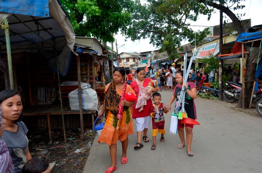 women and children with cleaning tools approach a home in Jakarta after flooding