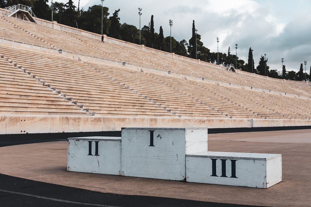 An old fashioned podium in an amphitheatre, with three levels for the three winners