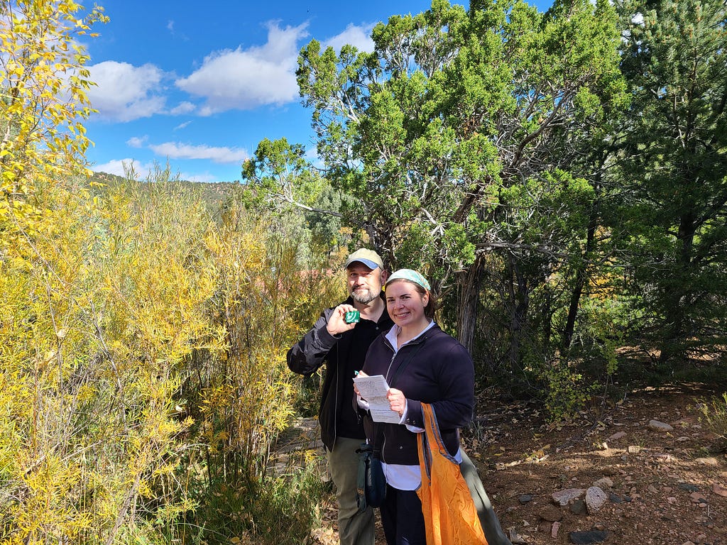 Dr. Henry “Trae” Winter and MaryKay Severino smiling outdoors with a notebook and an AudioMoth recorder.