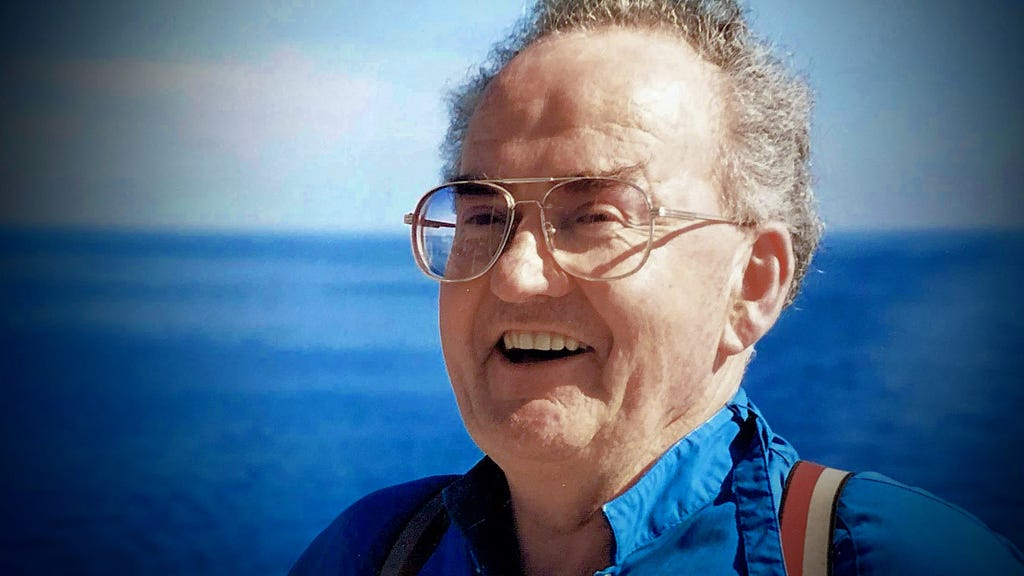 Smiling older man with glasses on the ocean