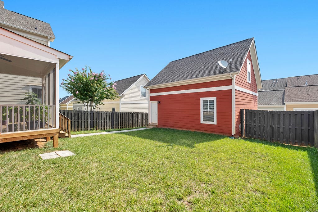 A suburban back yard bordered by houses and a wooden fence