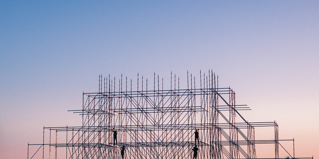 [Photo] Silhouette of four people on a steel-frame building construction.
