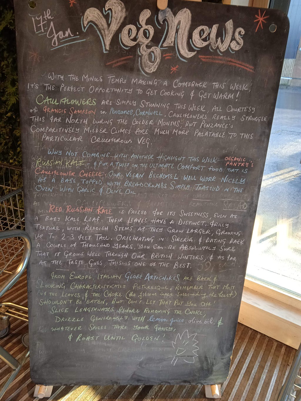 A chalk board outside Unicorn Grocery, Manchester, UK. The heading is “veg news”, followed by several paragraphs detailing the latest seasonal updates.