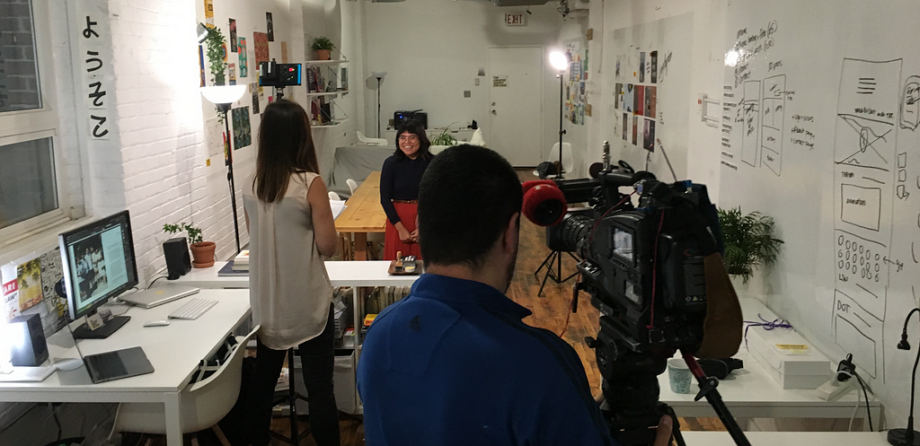 Man behind camera filming two women in an office.