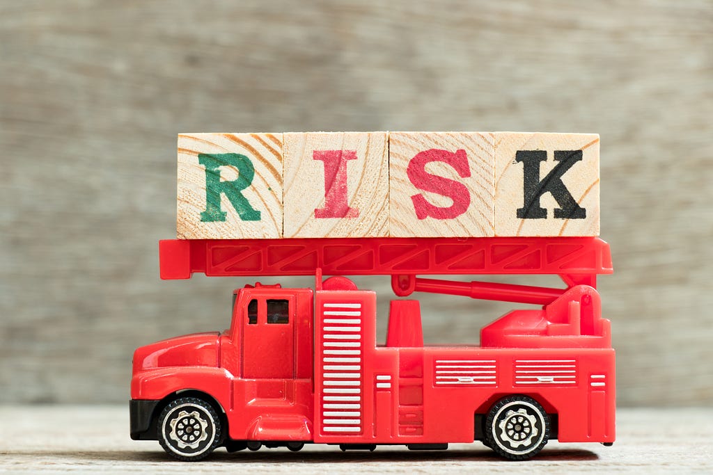 A toy fire truck carrying wooden blocks with letters spelling the word “risk”