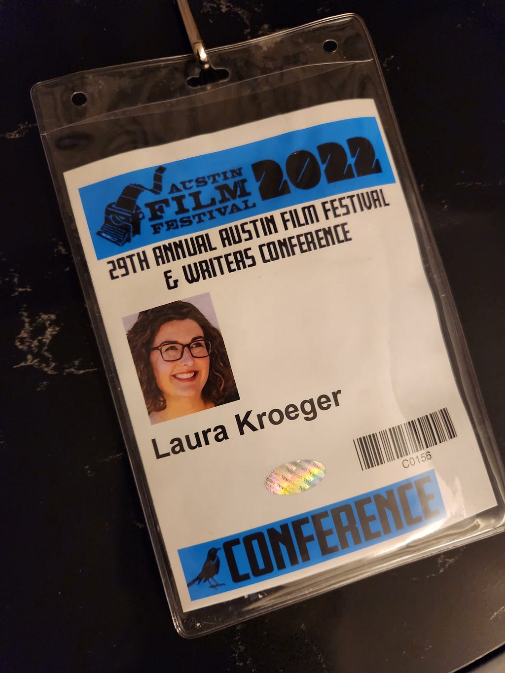 [ID: Laura’s Austin Film Festival badge from 2022, complete with an image that matches her social media profile photo.]