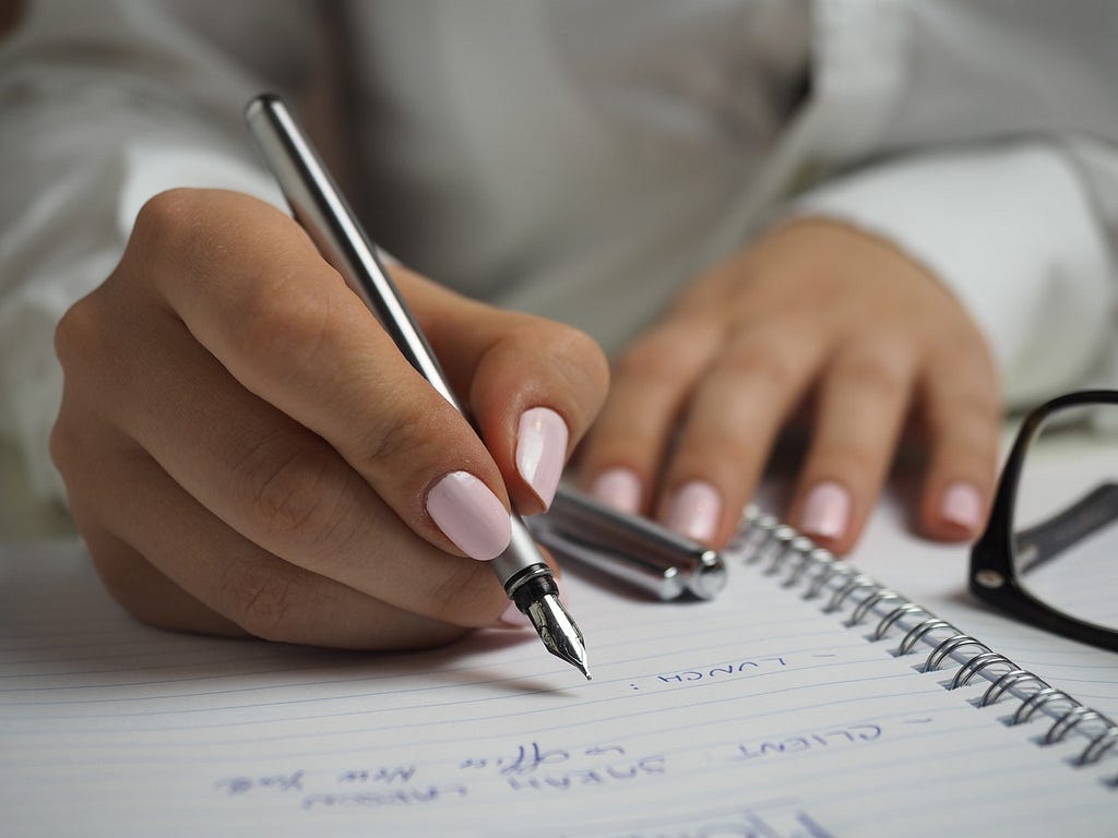 Woman’s hands writing in a notebook