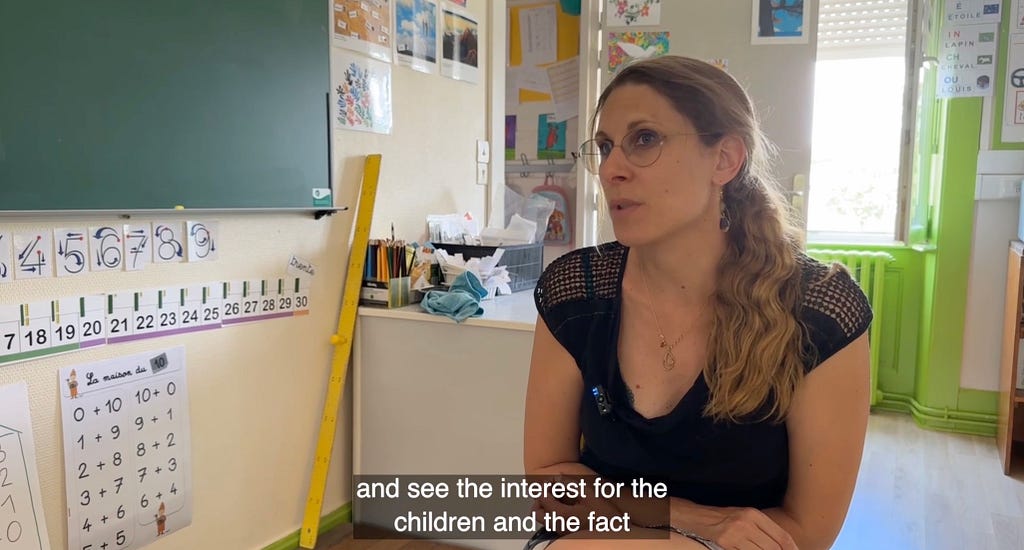 Teacher interview in her classroom with a close caption: “and see the interest for the children and the fact…”