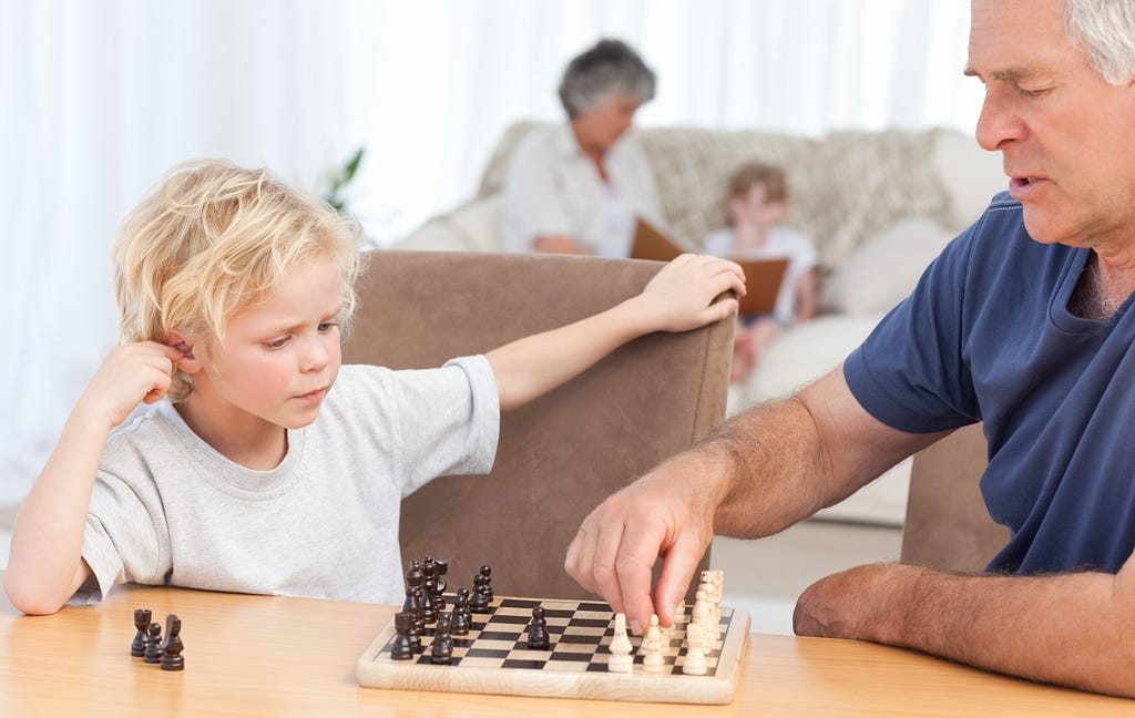 A grandfather teaching Chess to his grandchild