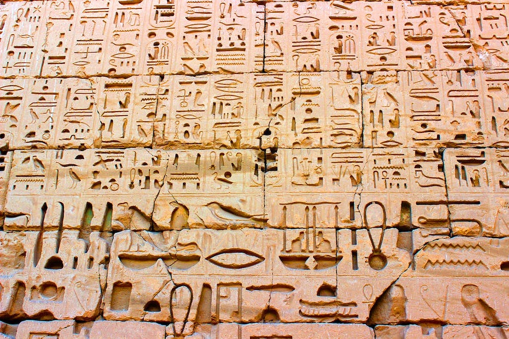 Photo of an stone wall with Egyptian hieroglyphs