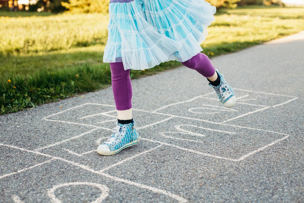 Closeup of girl playing jumping hopscotch outdoors