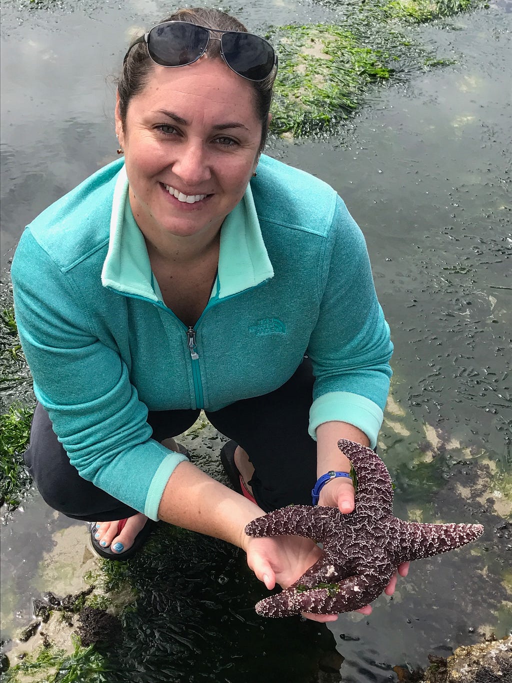 Women smiling while holding a starfish above water