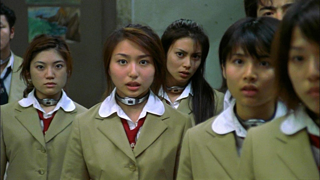 A group of young women all dressed in the same green suit with white collar are standing in a group.