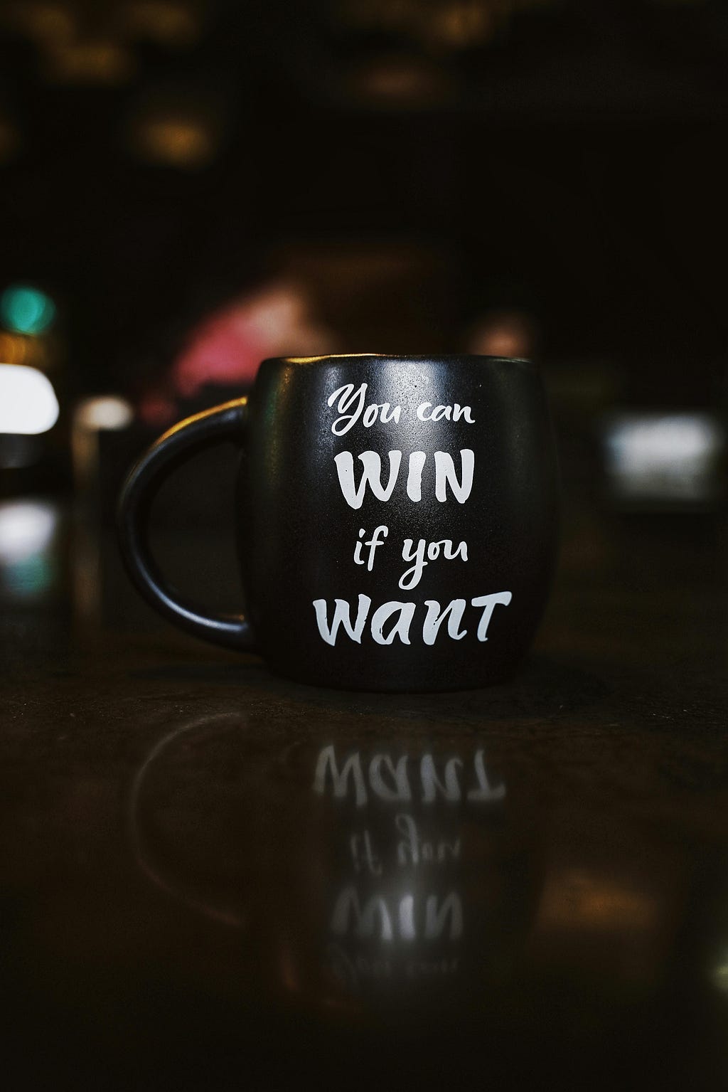 Close up photo of black mug that says “you can win if you want” in white font
