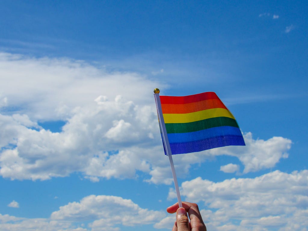 Rainbow flag waving in front of the sky