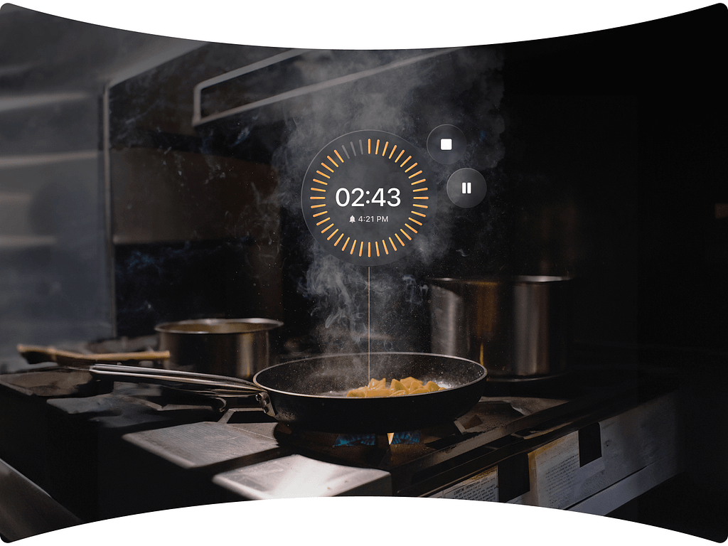 In a kitchen with a pan cooking on the stove, an AR timer overlay displays the countdown of 2 minutes and 43 seconds, with options to pause or stop.