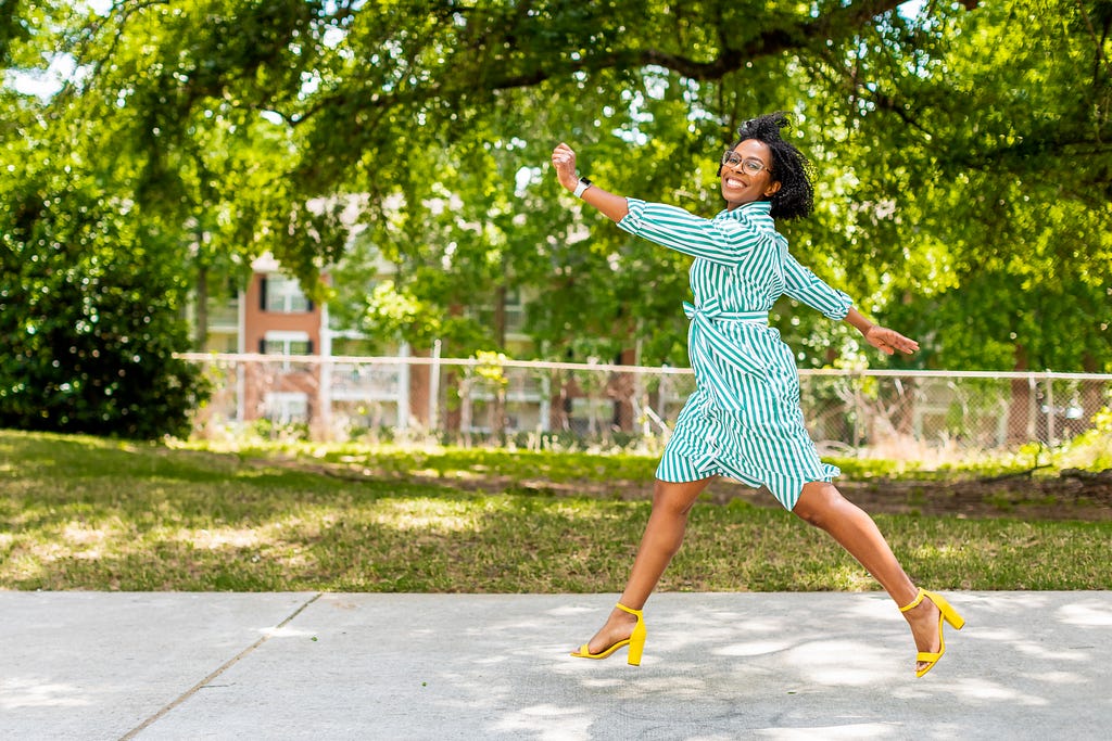 a picture of Shunta leaping in the air wearing a stripe dress and yellow shoes