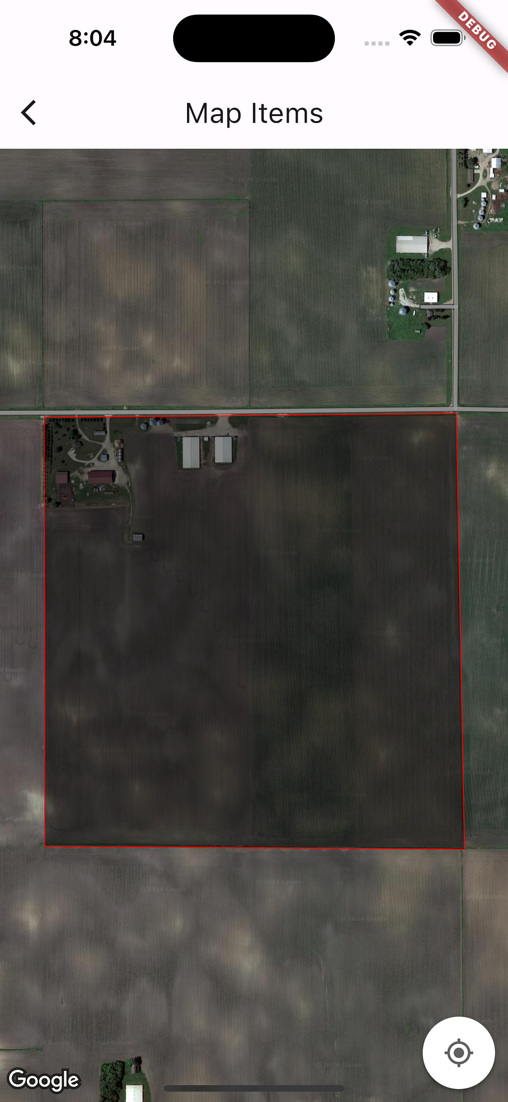 A screenshot of a map open on a smartphone. The map is showing satellite image of a farm in Northern part of USA. A polygon is drawn on the map. The Polygon has four sides, colour of each side is red and the polygon is filled with translucent black color.