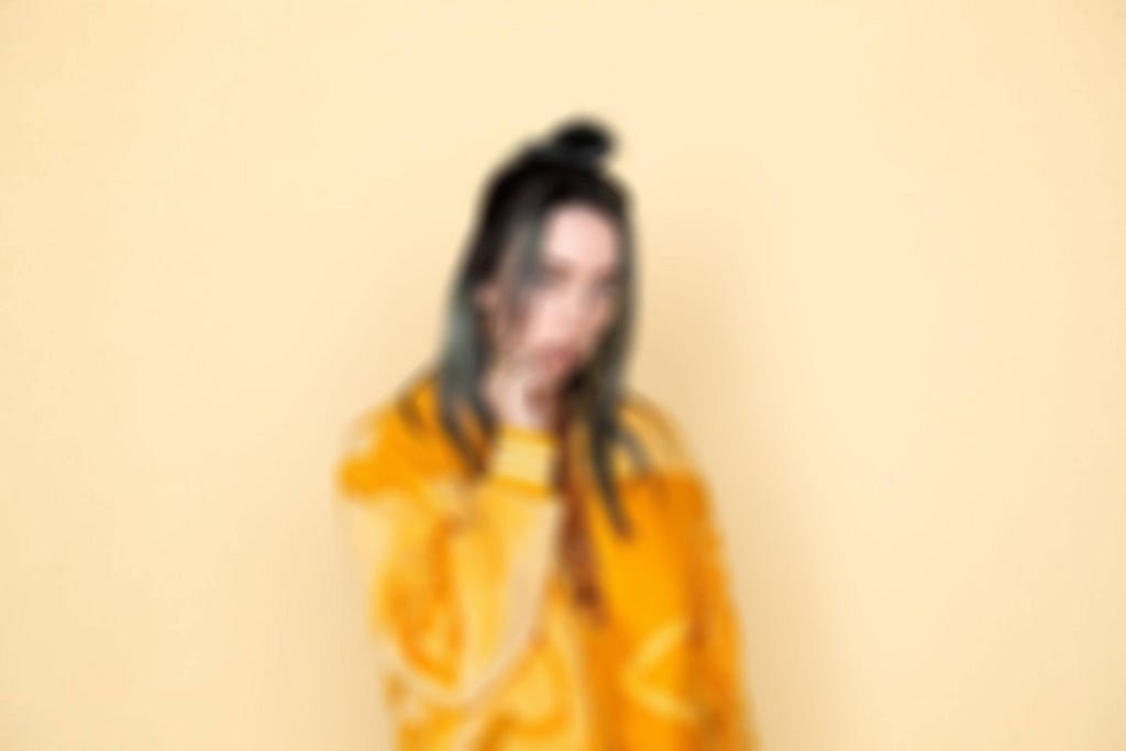 Billie Eilish in an orange jacket blurred out.