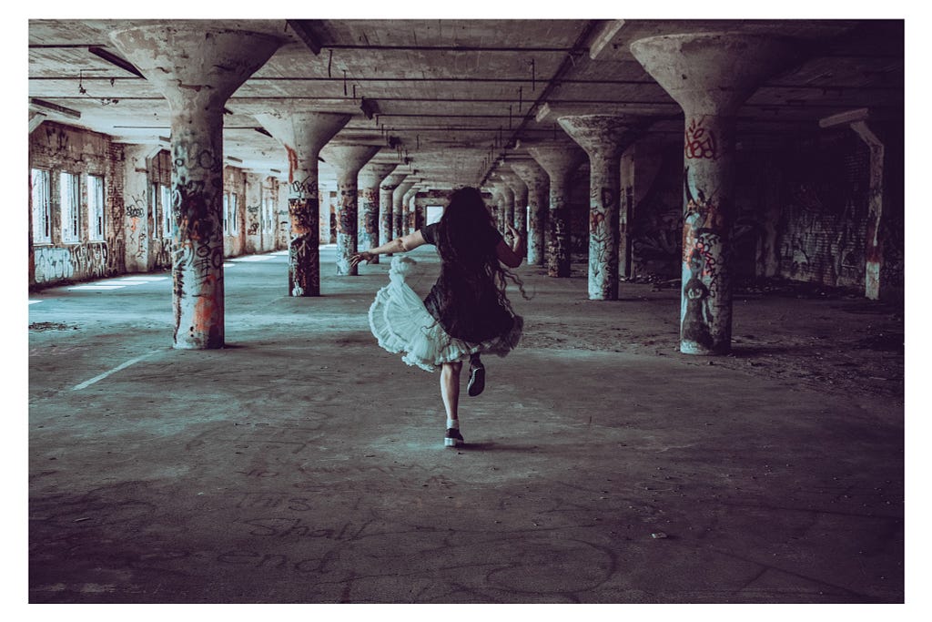 photo of the author by Christina Ramirez — A woman with messy hair skips merrily through an abandoned factory