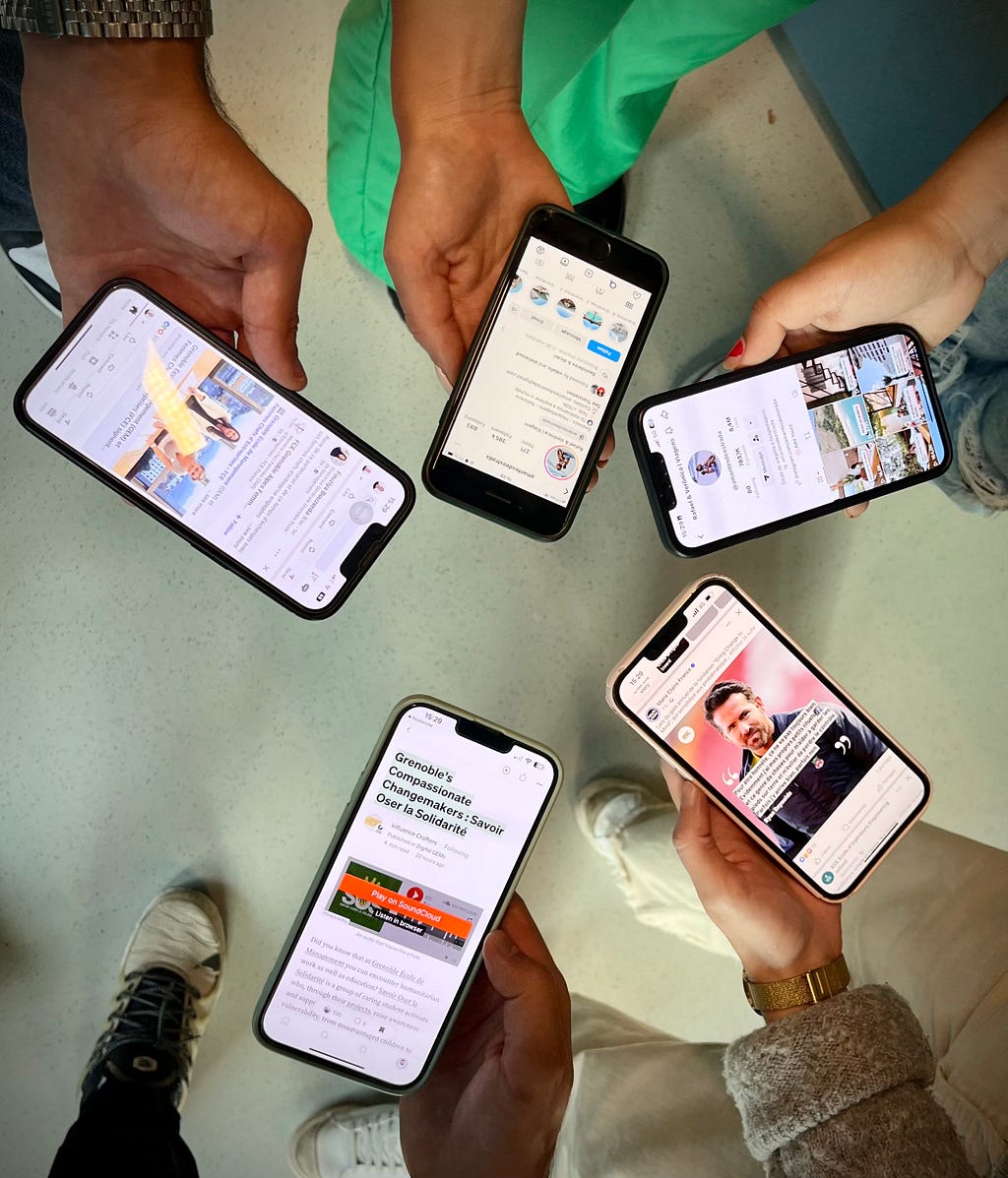 The picture shows five hands of GEM (Grenoble Ecole de Management) students holding their phone, and more precisely, their social media and social networks.