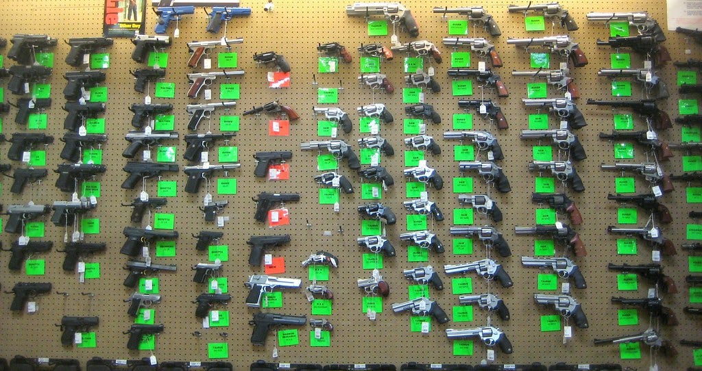 Multiple handguns with price tags on a wall.