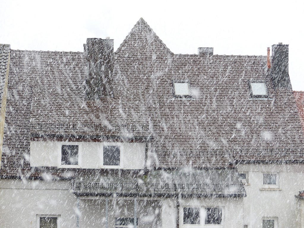 A large house with brown tiled roof and white walls in a snowstorm