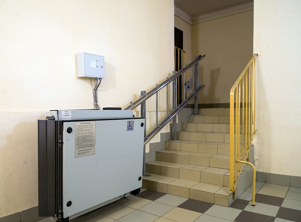 An accessible ramp folded against the wall, in front of a staircase leading to a room
