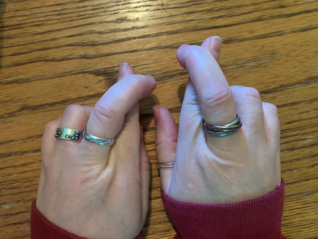 Two Caucasian hands side by side with crossed fingers on each hand.