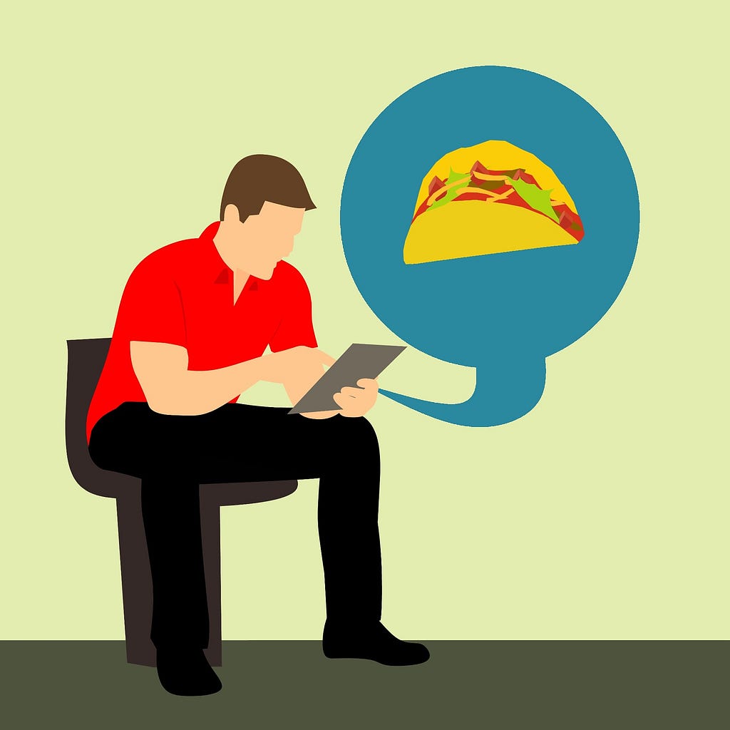 A man sitting and using a tablet with a taco on the screen.