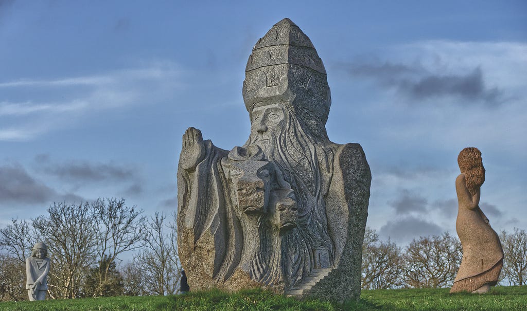 Sculpture de « Korneli » réalisée par l’artiste Goulven Jaouen. Saint Cornély, Sant Korneli en breton, est le plus connu des saints protecteurs du bétail. Selon la légende, Cornély, pape à Rome, était poursuivi par des soldats païens. Deux bœufs l’accompagnaient qui portaient ses bagages. Un soir, il arriva devant la mer. Les soldats le serraient de près, rangés en bataille. Il se cacha dans l’oreille d’un bœuf et transforma ses ennemis en pierre.