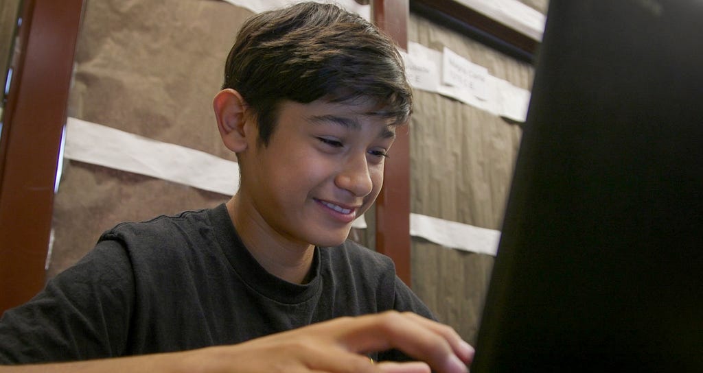 A young student works on a laptop