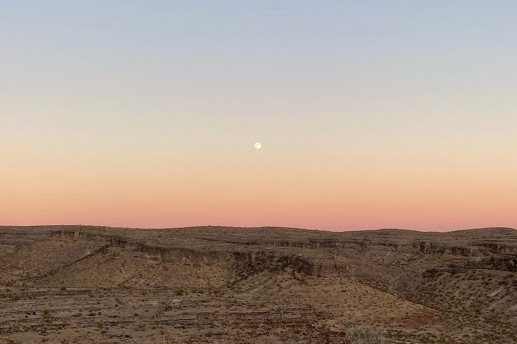 Sunset landscape of barren Nevada desert with full moon.
