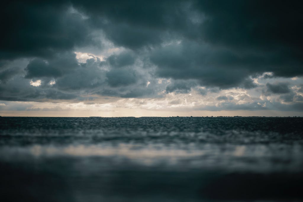 An ocean with a stormy sky above it