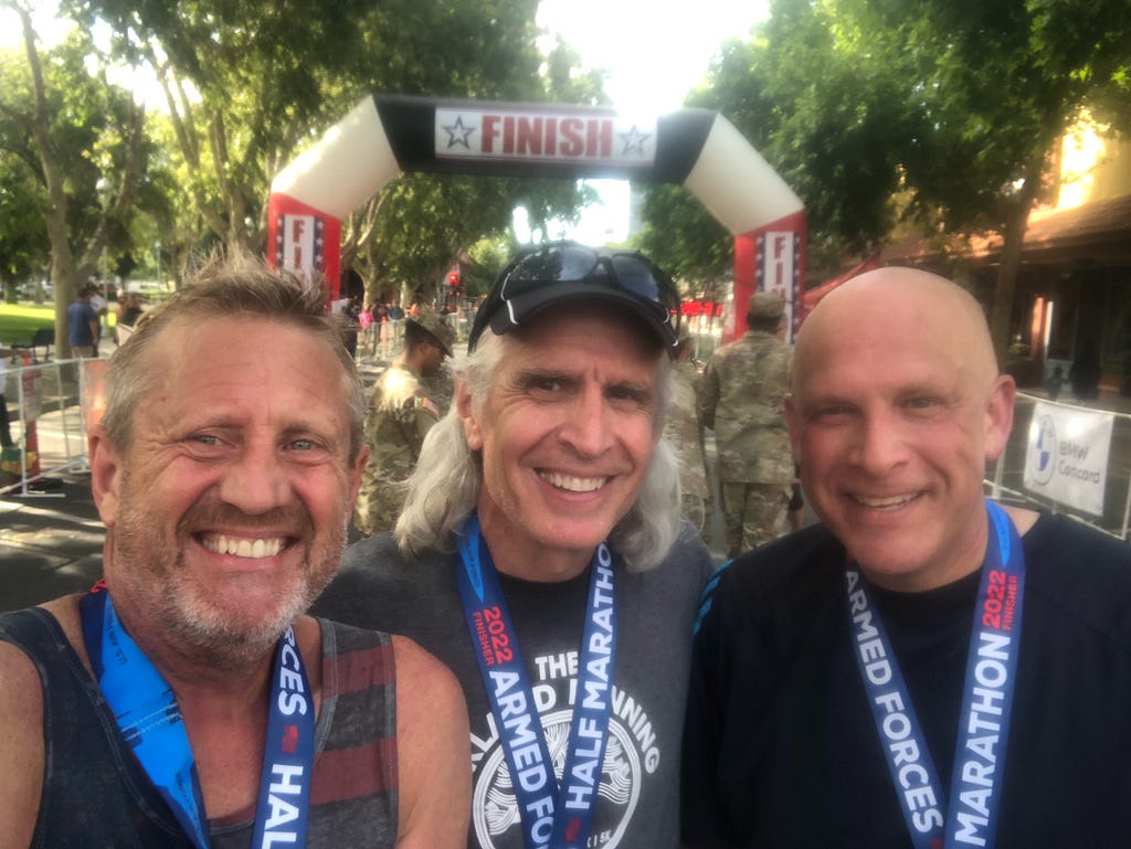 Three smiling runners at the finish of a half marathon event