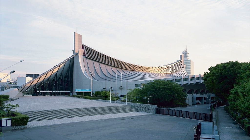 Yoyogi National Gymnasium; long and curved concrete and metal building.