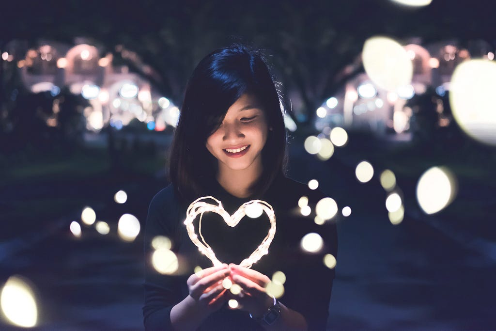 Woman holding lights in the shape of a heart.
