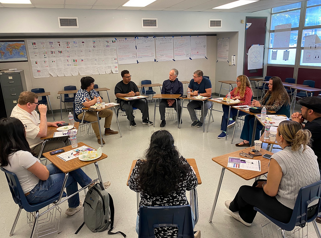 Group of people sitting in a circle in a high school classroom.