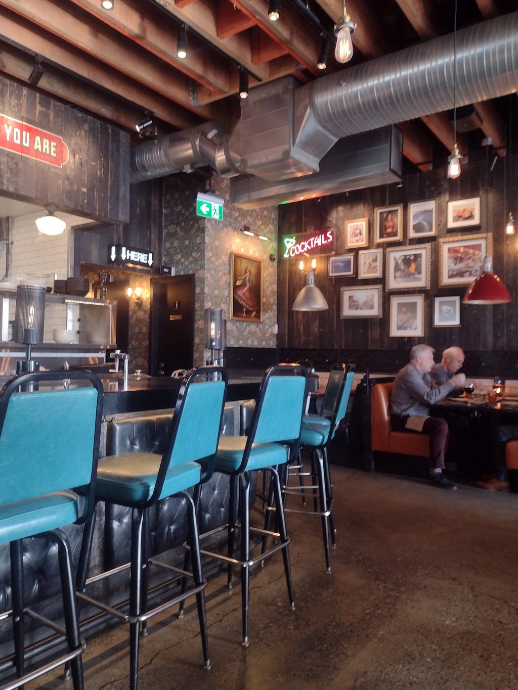 inside Brown’s Crafthouse in Vancouver BC — blue bar chairs, booth seats and pictures on the wood-paneled walls
